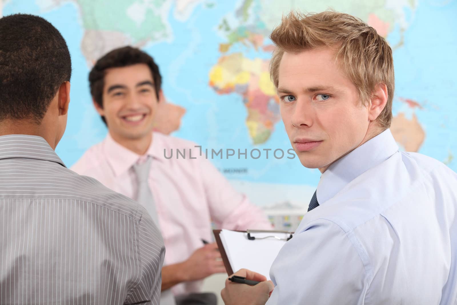 Young businessman holding a clipboard during a meeting by phovoir