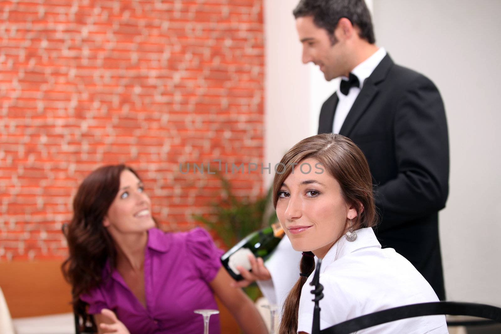 wine waiter showing a sparkling wine bottle to customers by phovoir