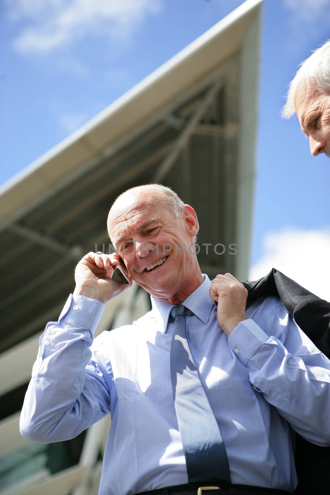 Smiling businessman on the phone by phovoir