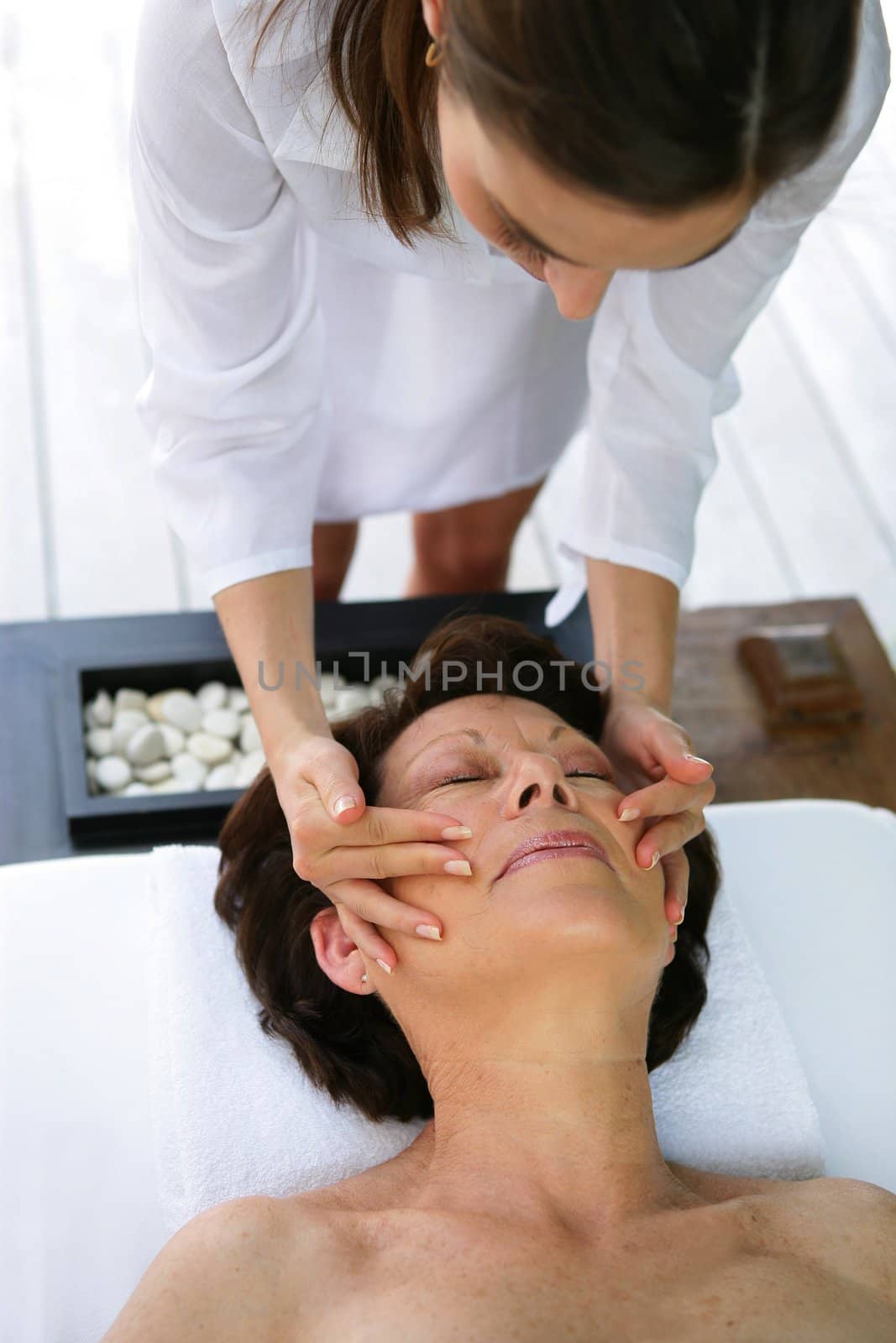 senior woman having a massage in a spa center by phovoir