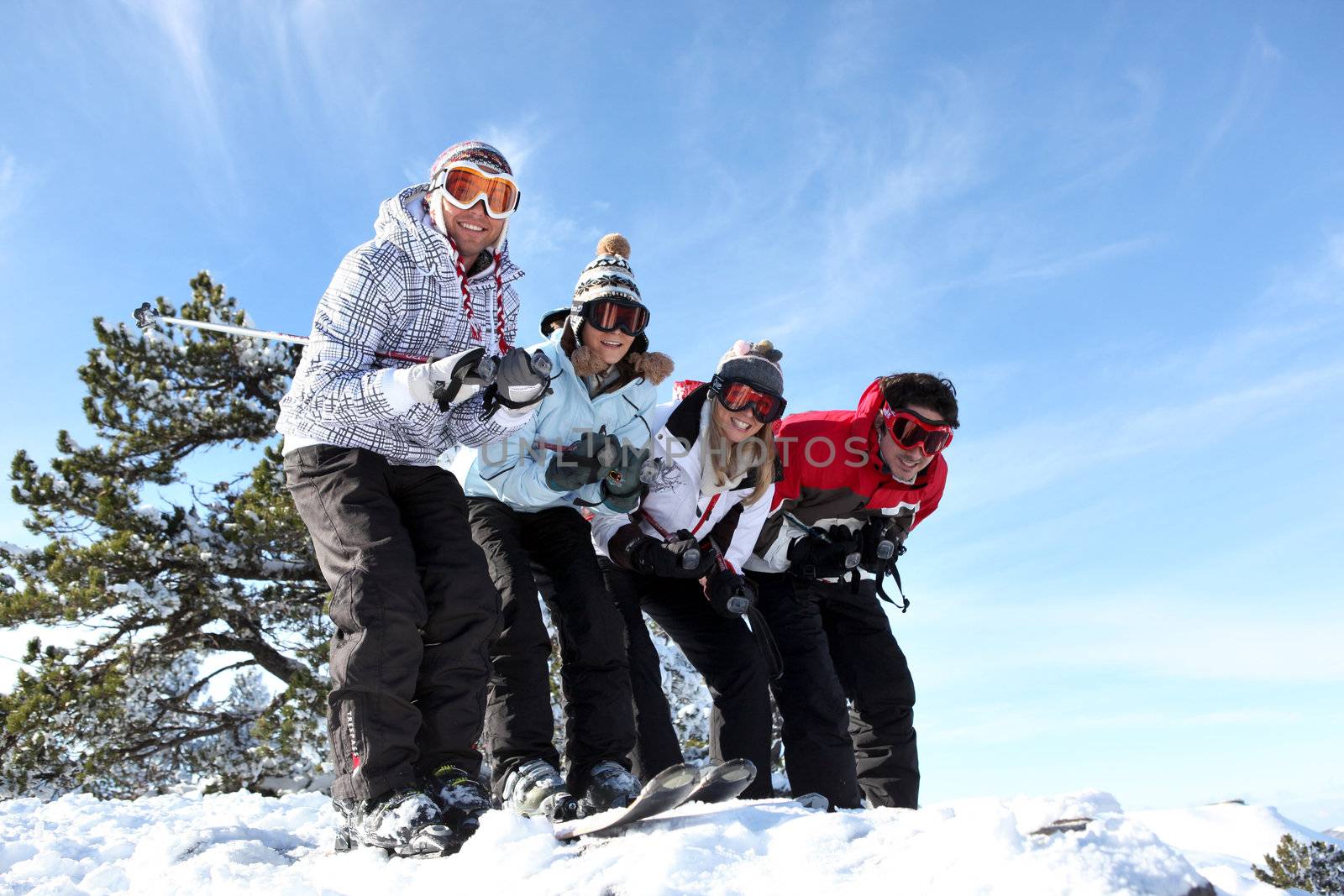 Four friends skiing together on holiday by phovoir