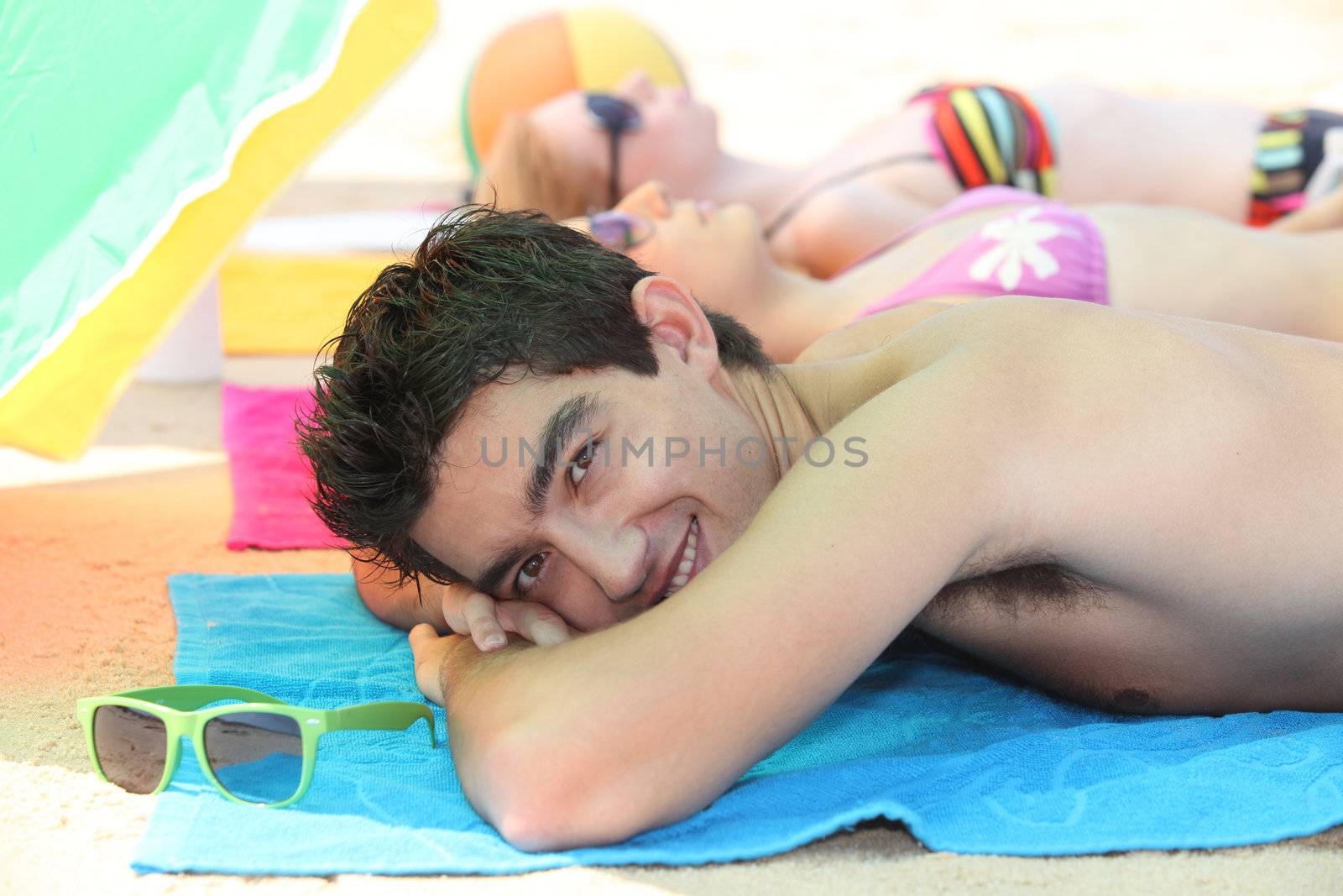 Three young people sunbathing by phovoir