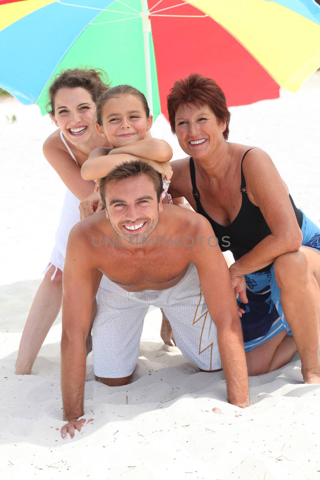 Family holidaying on a sandy beach by phovoir