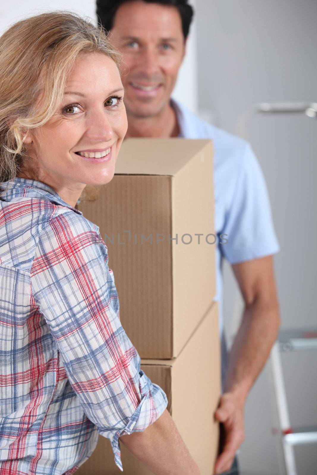 Couple carrying packing boxes into new home