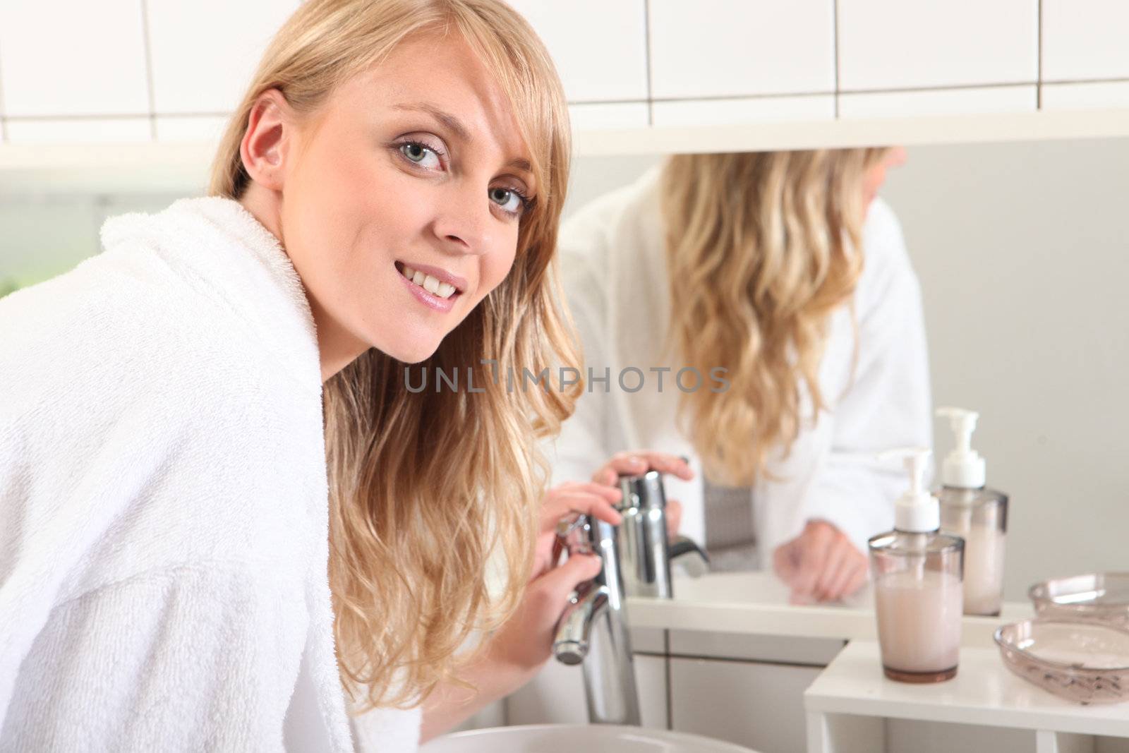 young blonde woman dressed in bathrobe in the bathroom