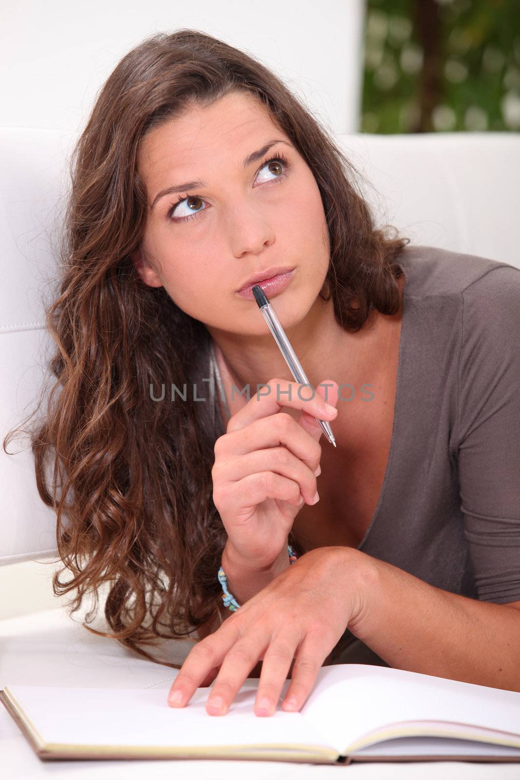 Young woman thinking about what to write in her book