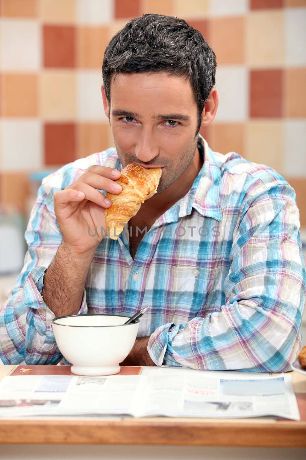Handsome man eating a croissant