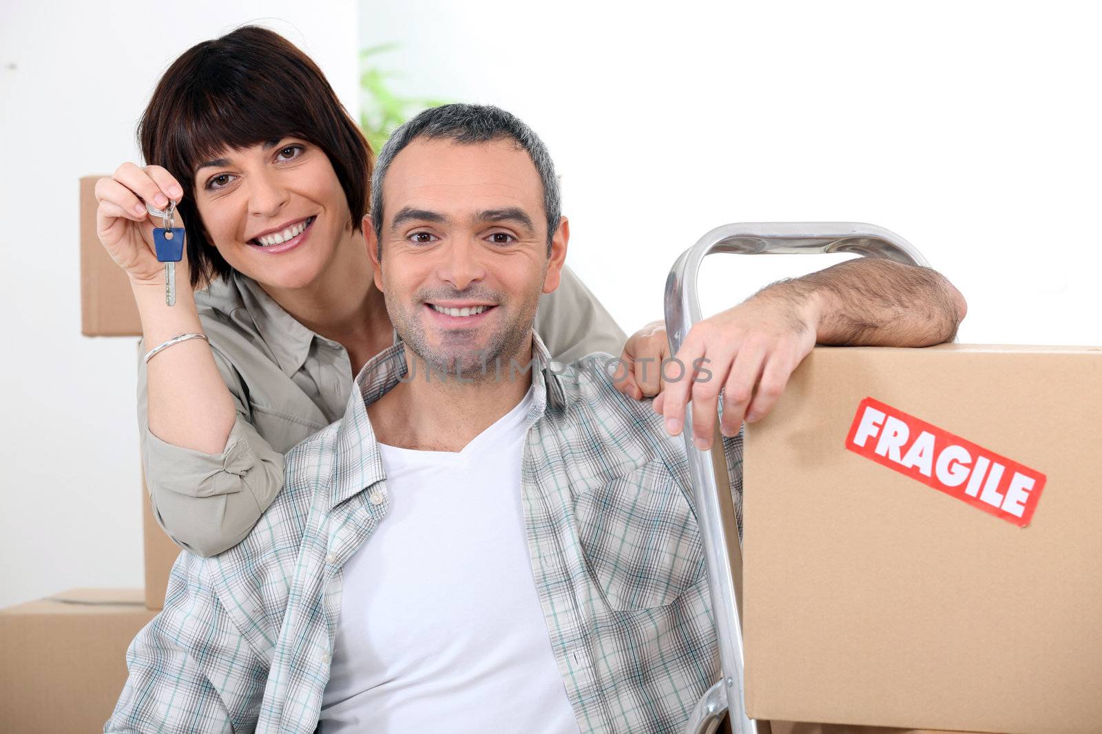 Couple moving into new home with doorkeys and boxes marked fragile