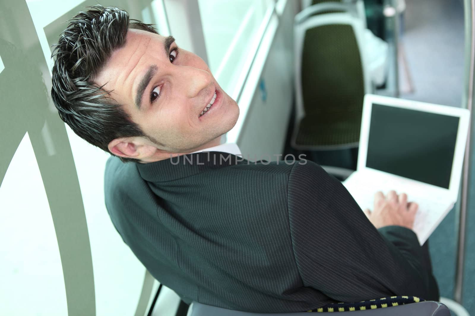 Young brown-haired man in a bus with computer