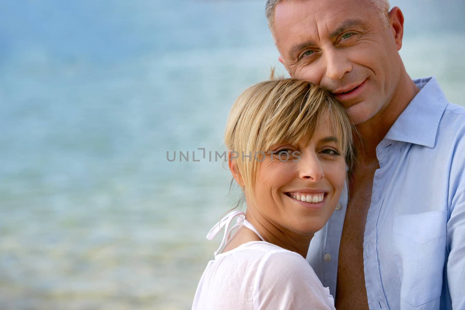 Couple stood hugging on romantic beach by phovoir