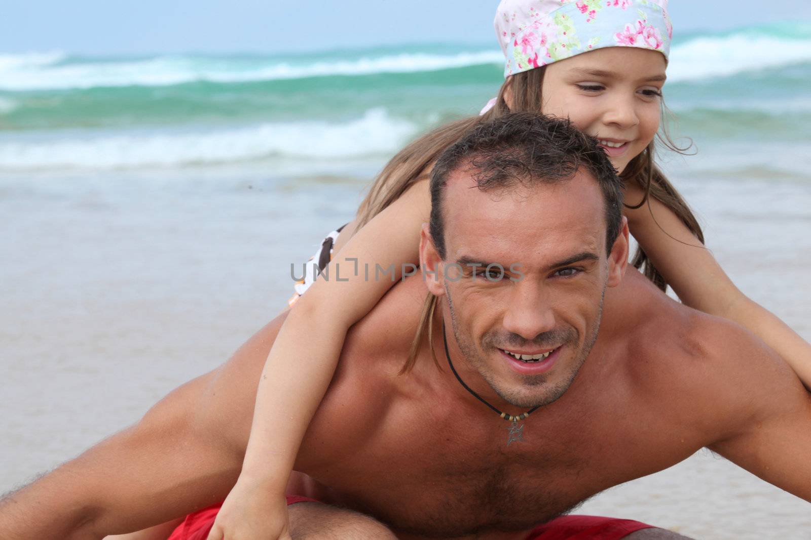 a little girl and her father playing on the beach