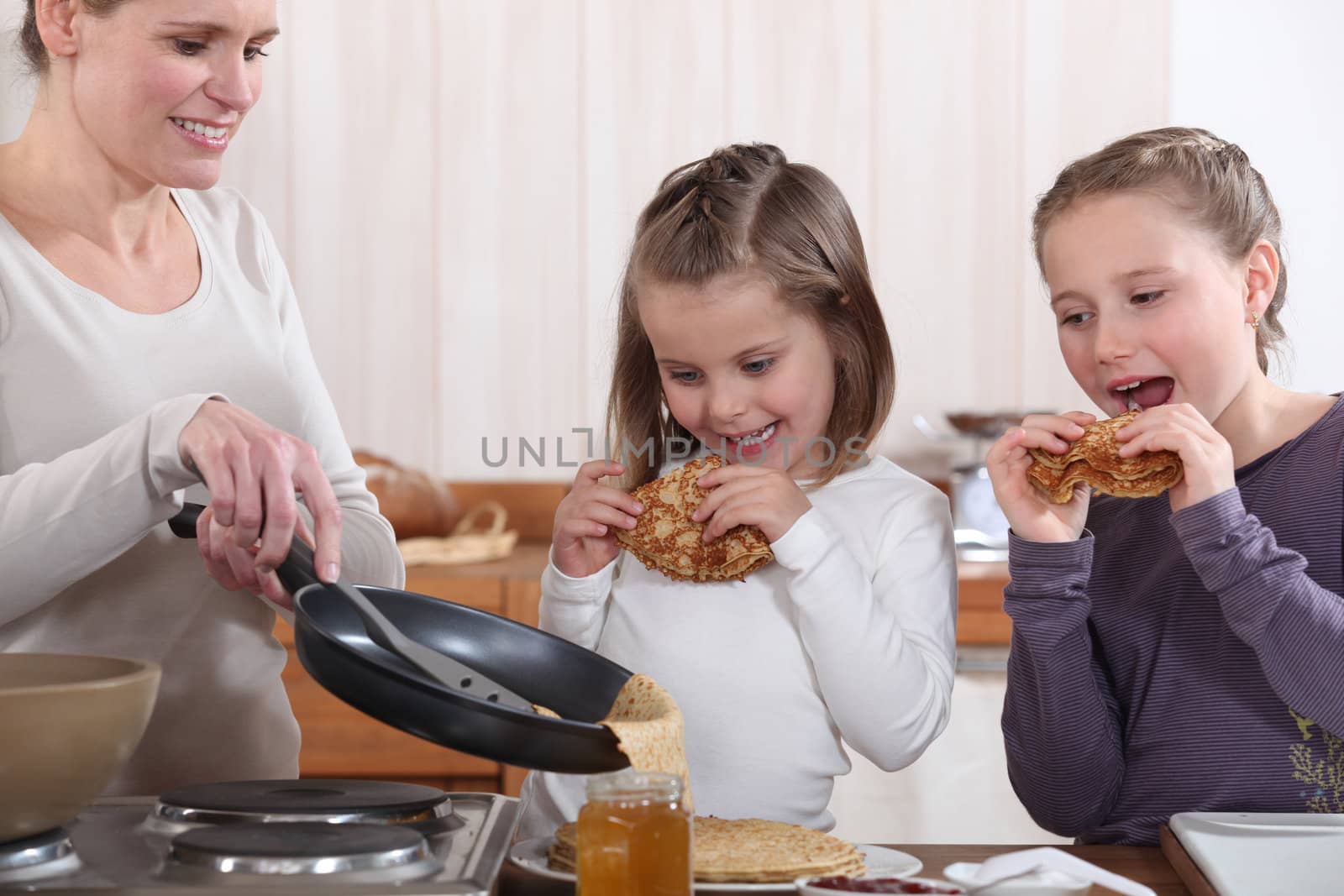 A mother making crepes for her daughters.