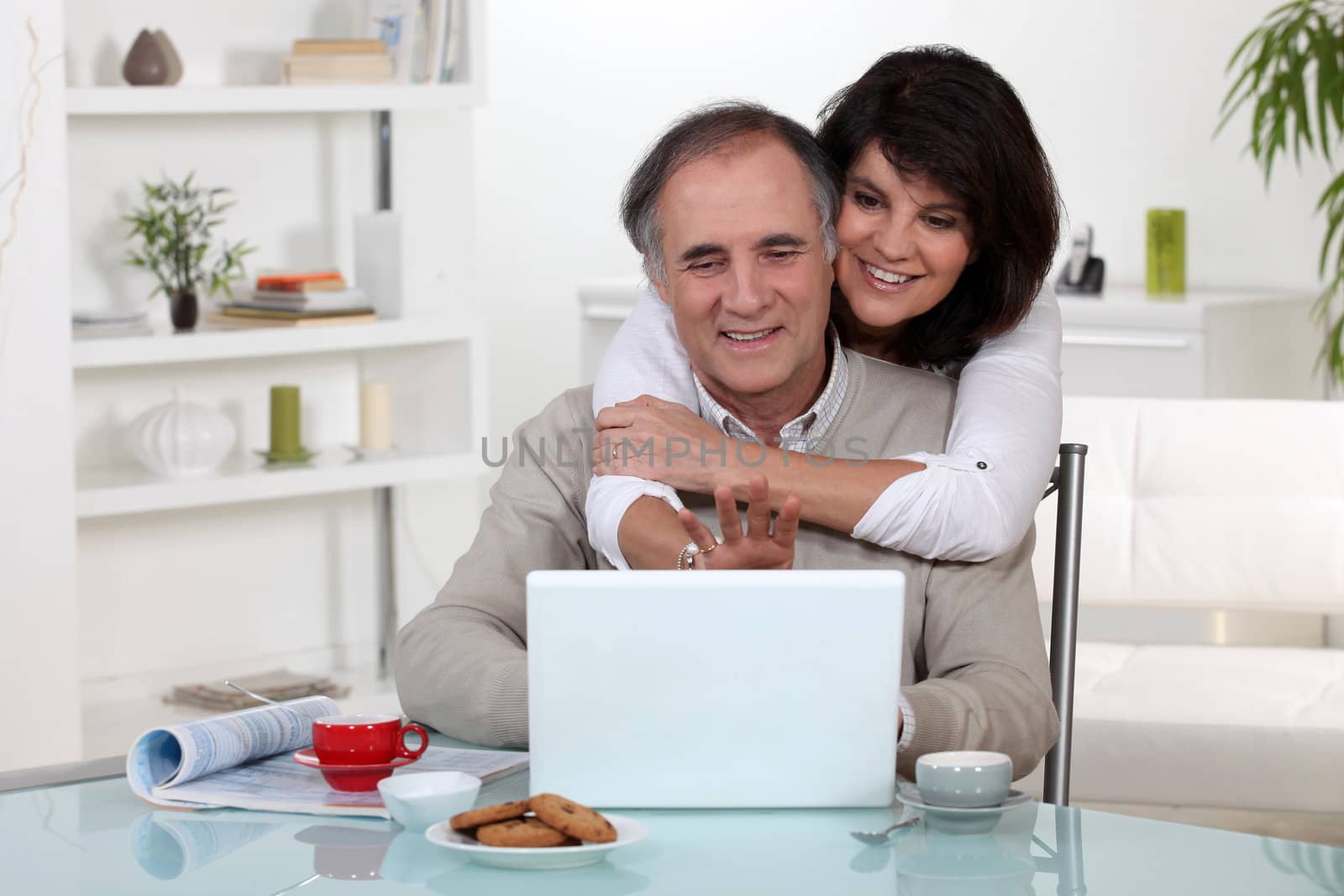 Couple smiling in front of their laptop by phovoir