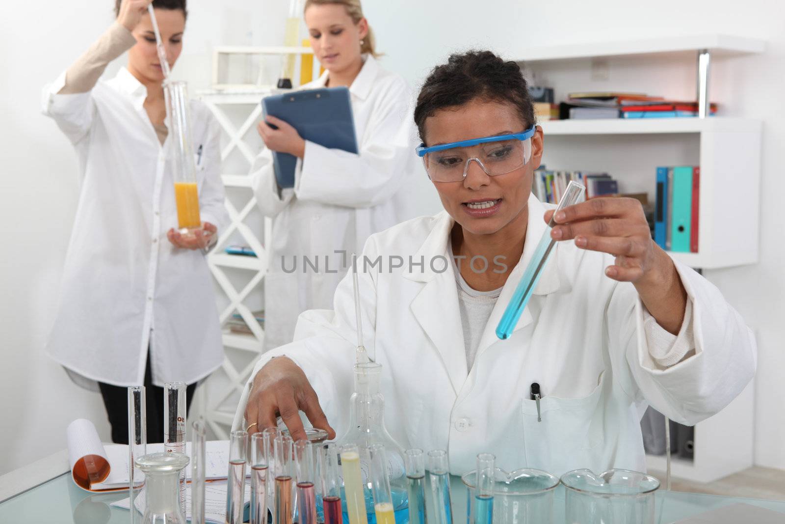 female trio in lab with test-tubes by phovoir