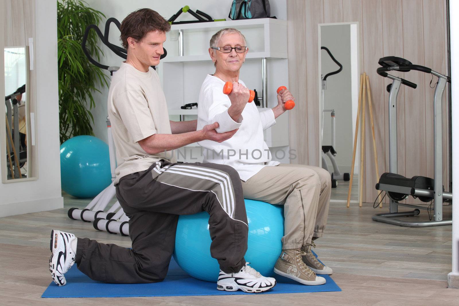 Woman working out with the help of her personal trainer by phovoir