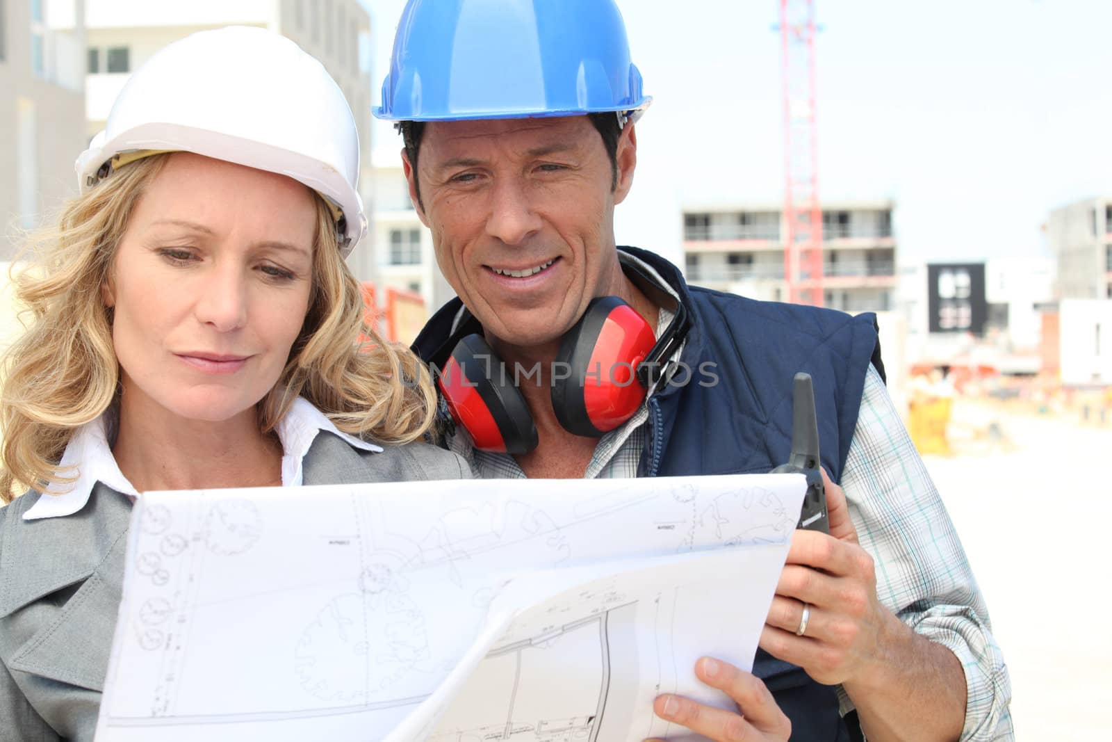 Construction worker looking at an engineer's drawing by phovoir