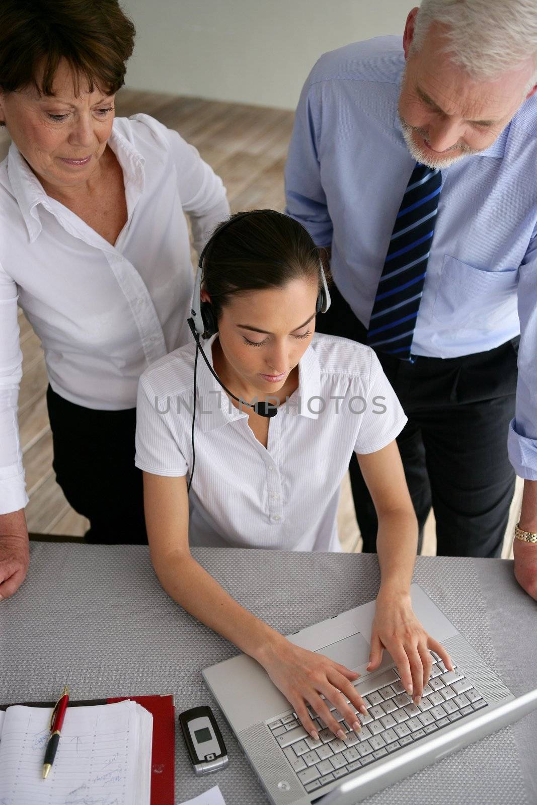 Business couple overseeing a woman talking through a headset