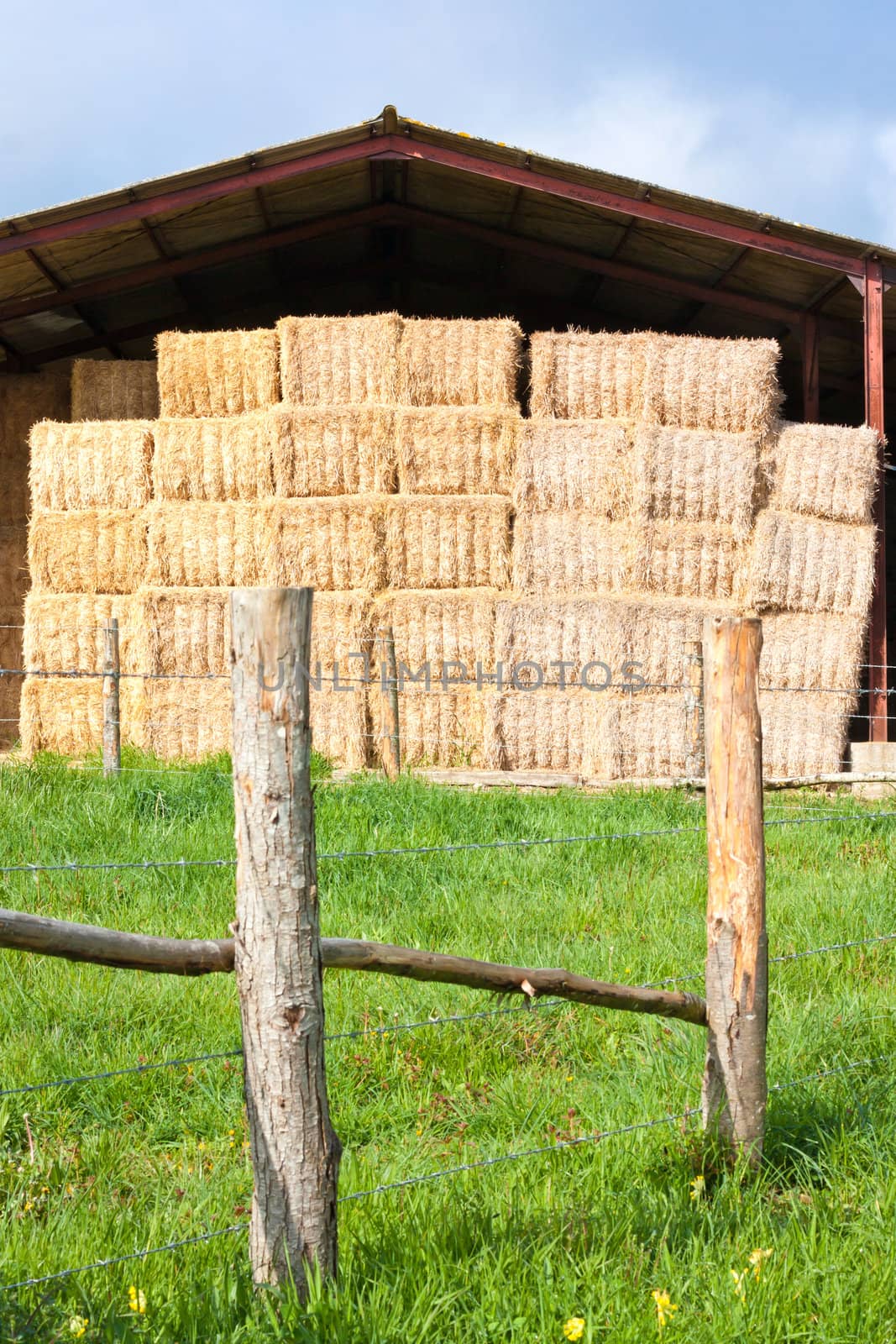 Haystack stored on a French farm with a fence in the foreground