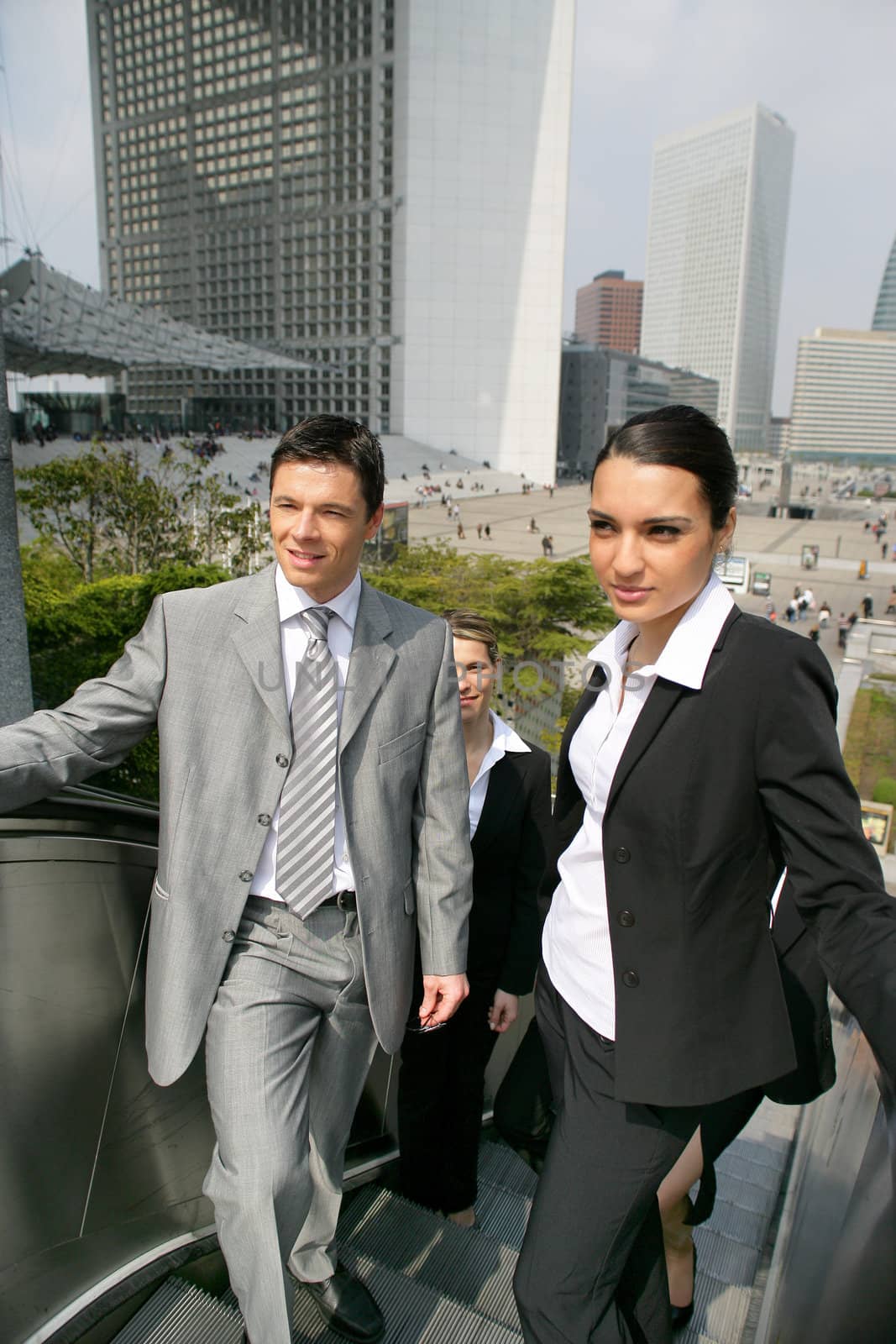 Businesspeople using the escalator by phovoir