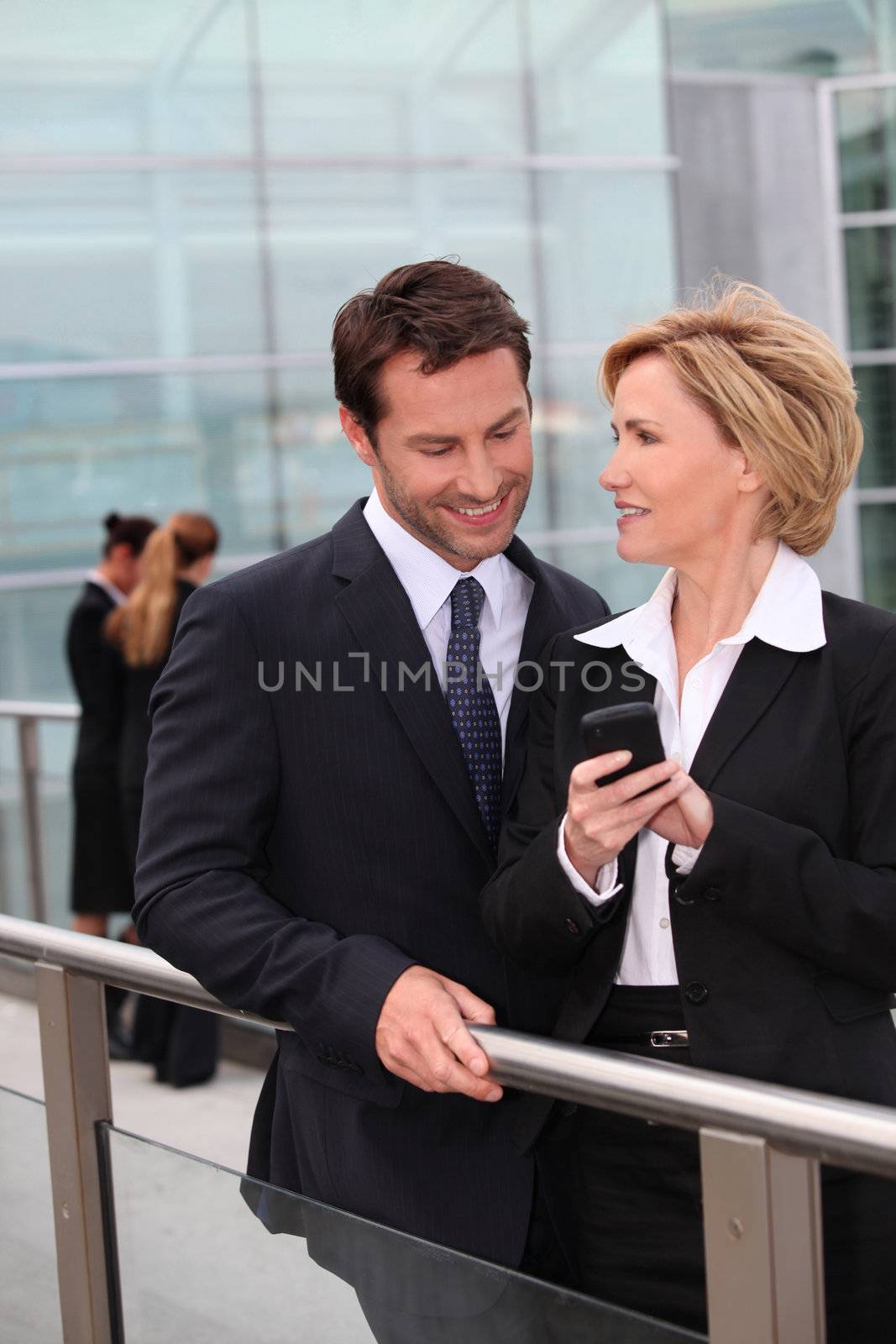 Businessman and businesswoman watching mobile phone outdoors