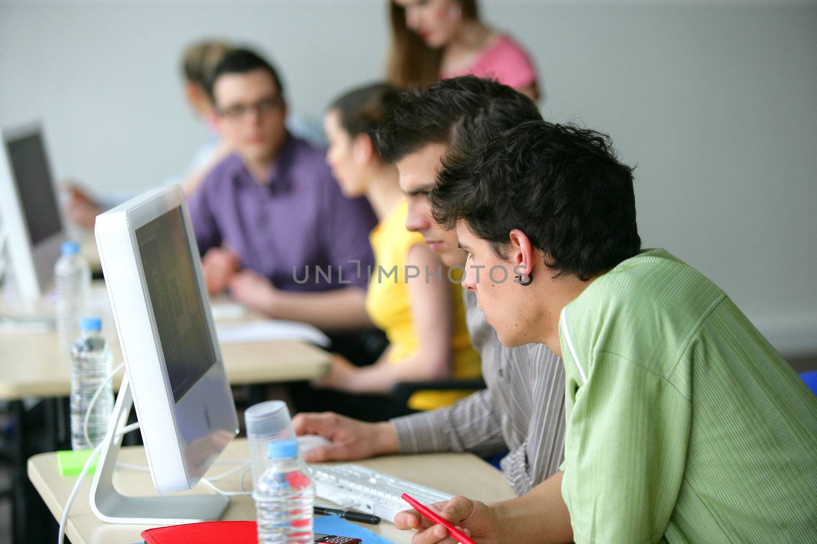 Young men using a computer in the classroom by phovoir