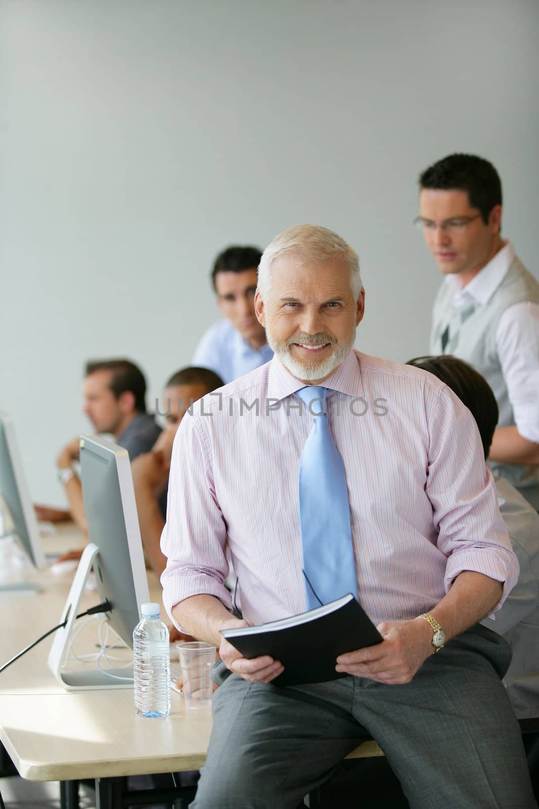 Senior manager sitting on a desk in front of his team