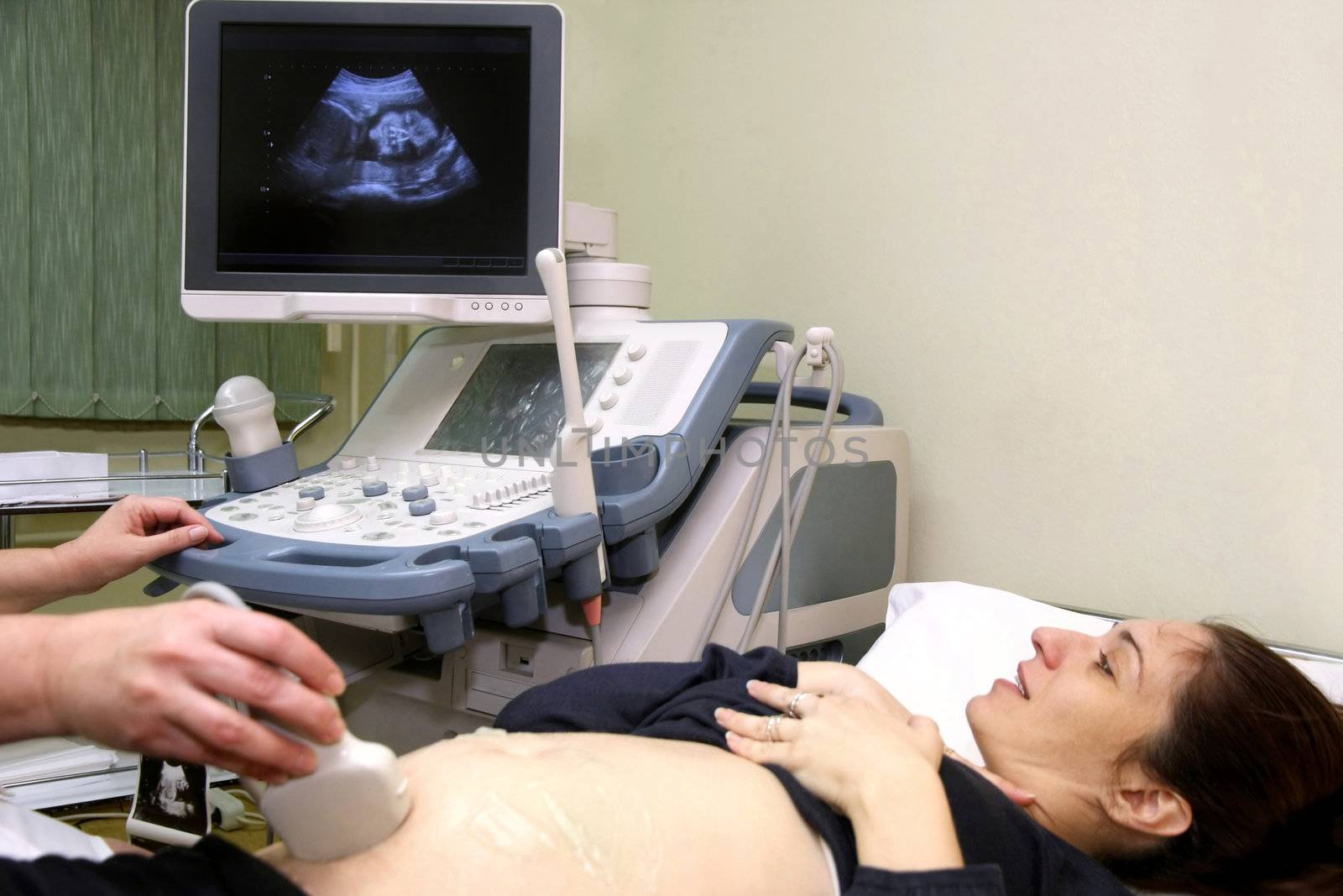 Pregnant woman and doctor hand's with ultrasound equipment during ultrasound medical examination 