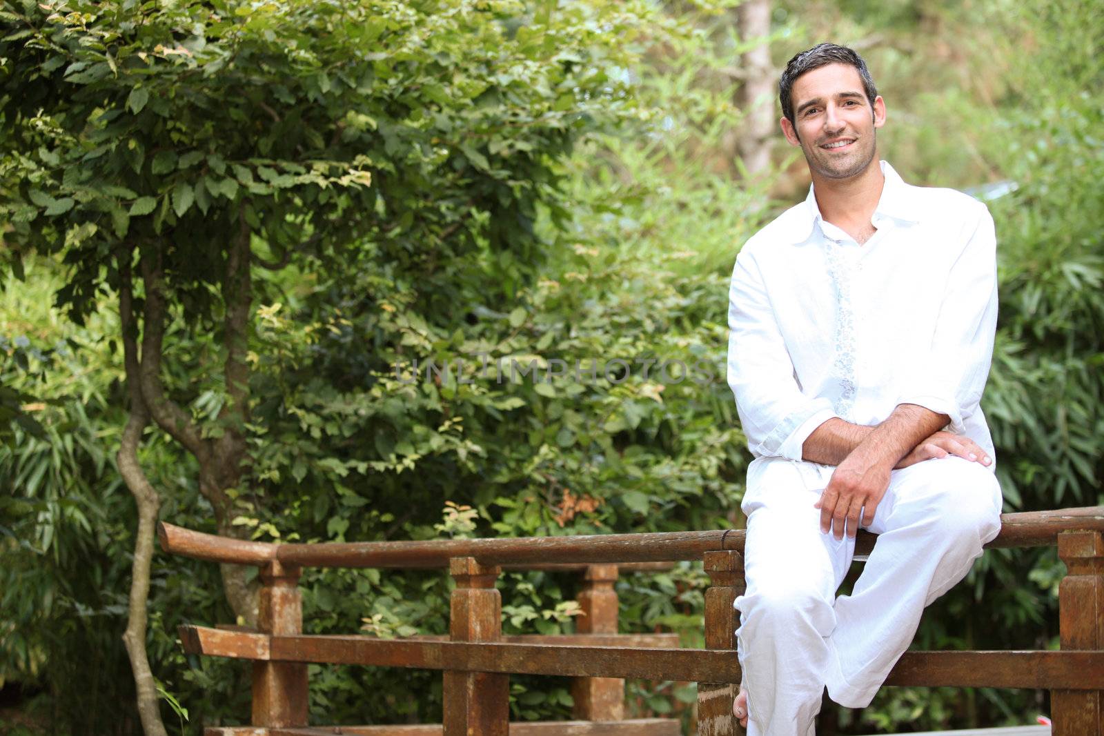 Man sitting on a Japanese style wooden fence by phovoir