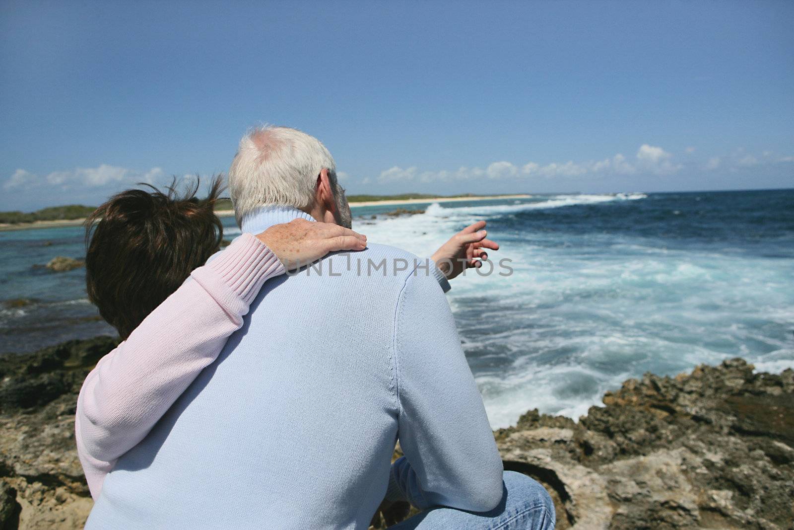 Senior couple pointing towards the sea