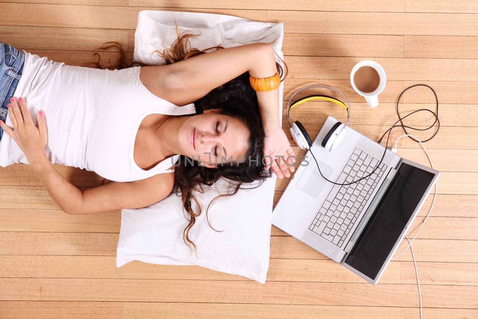 A girl laying on the Floor after surfing on the Internet with a Laptop.