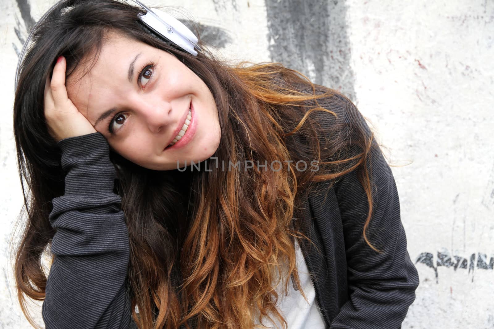 A young woman enjoying Music and sitting on the pavement.