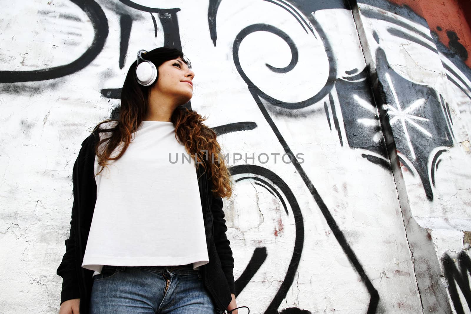 Girl listening to Music while leaning on a Wall.