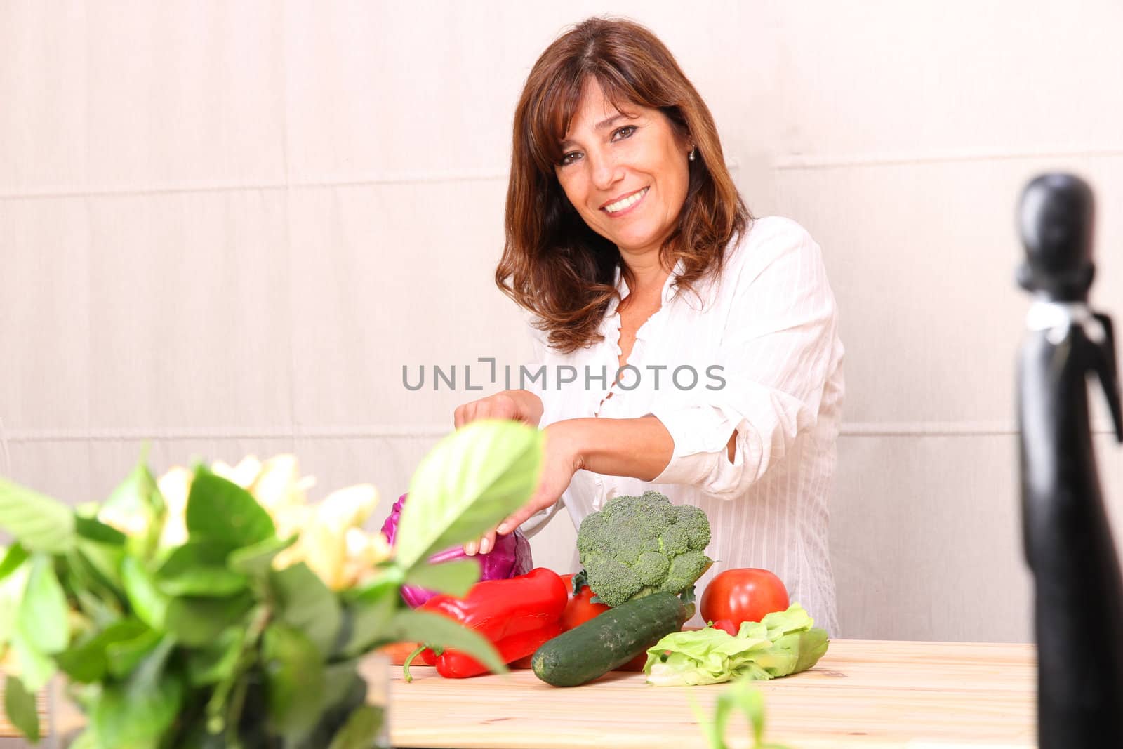 A beautiful mature woman cutting vegetables in the kitchen.