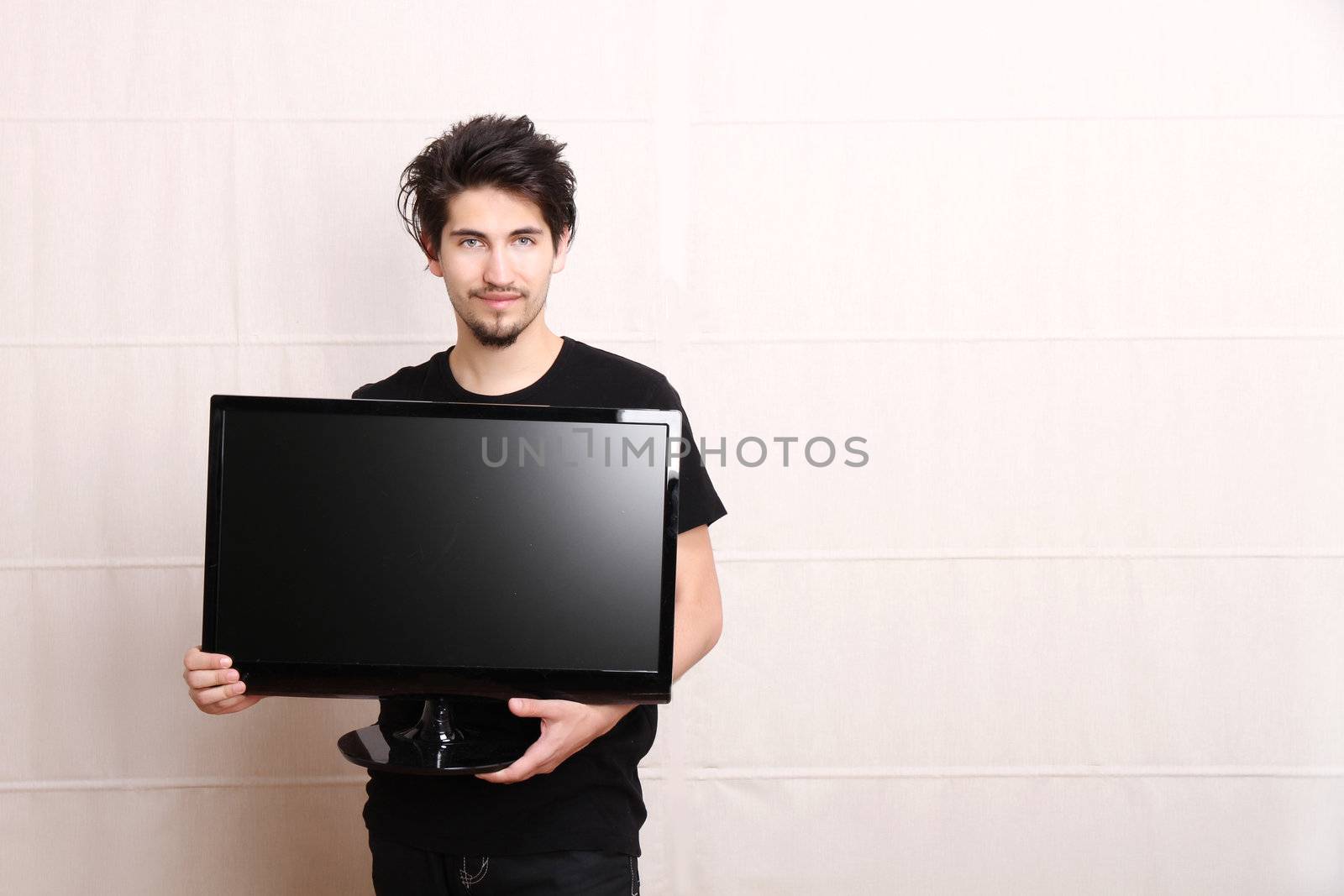 A young hispanic man holding a flatscreen TV.