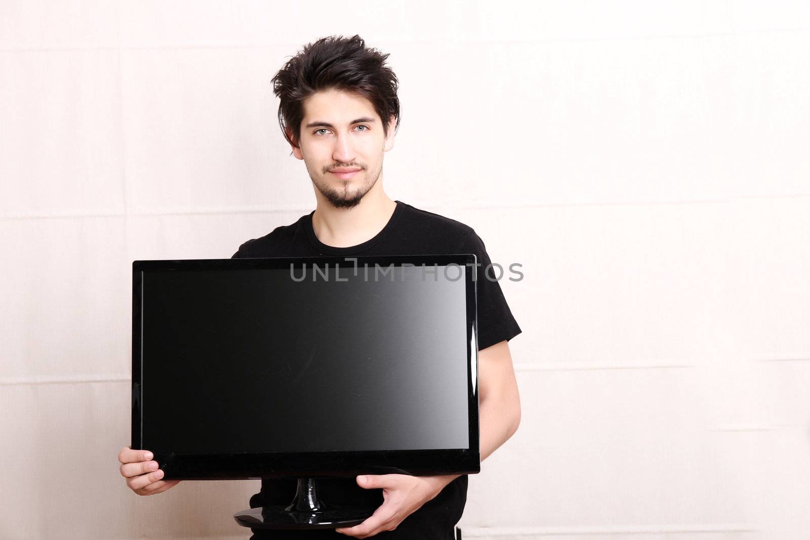 A young hispanic man holding a flatscreen TV.