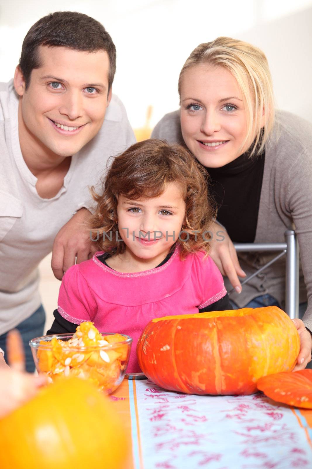 Young family carving pumpkins by phovoir