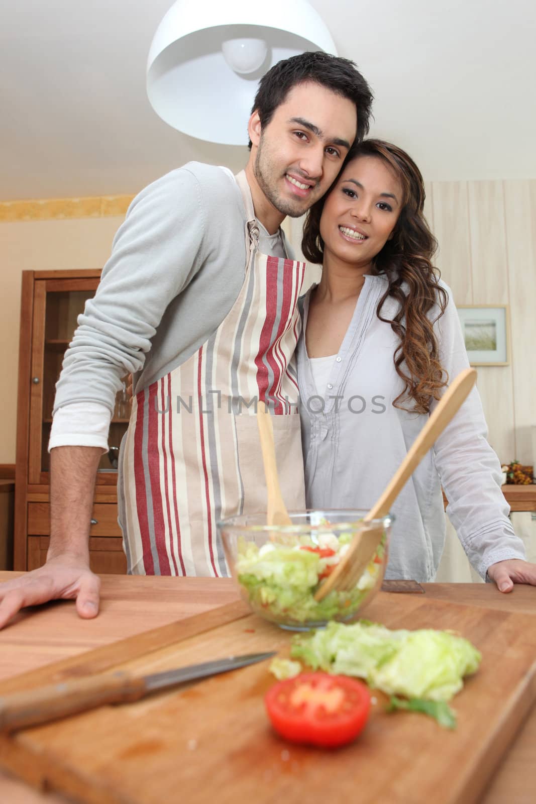 Couple making a salad in the kitchen by phovoir