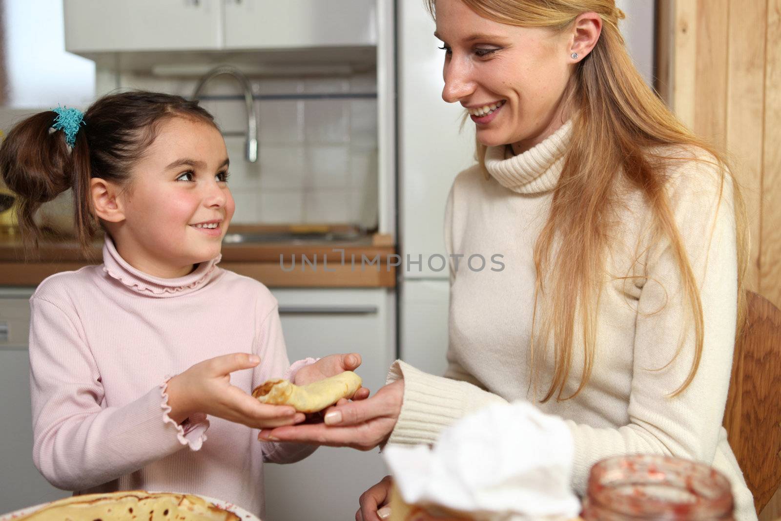 Little girl giving her mother a crepe