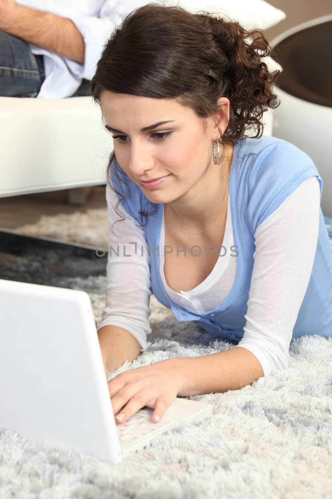 Young woman using a laptop on the floor at home by phovoir