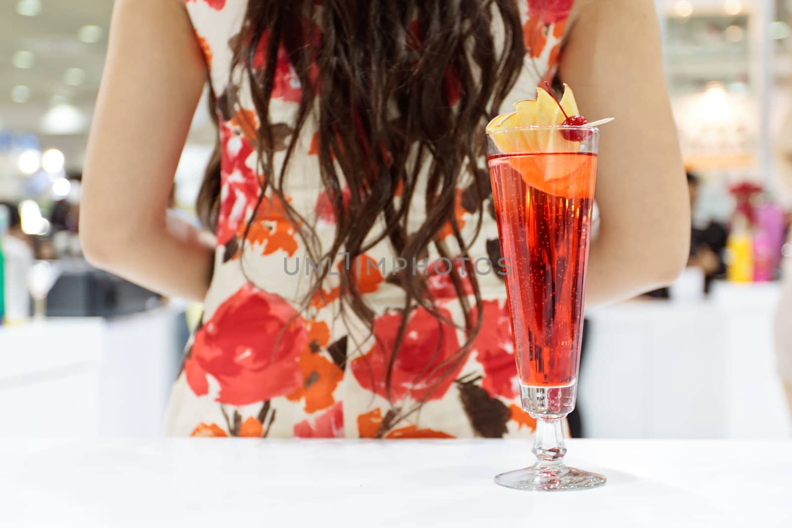 A tall glass of cocktail "Eliza" with a girl's back and hair on background