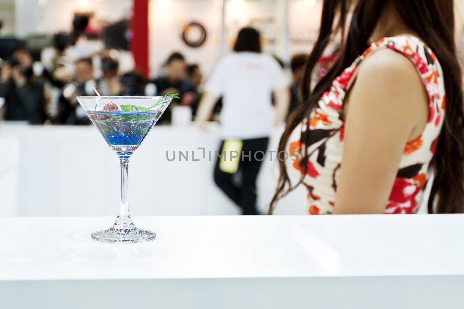 A glass of Blue Laguna cocktail with a sexy girl on background by dsmsoft