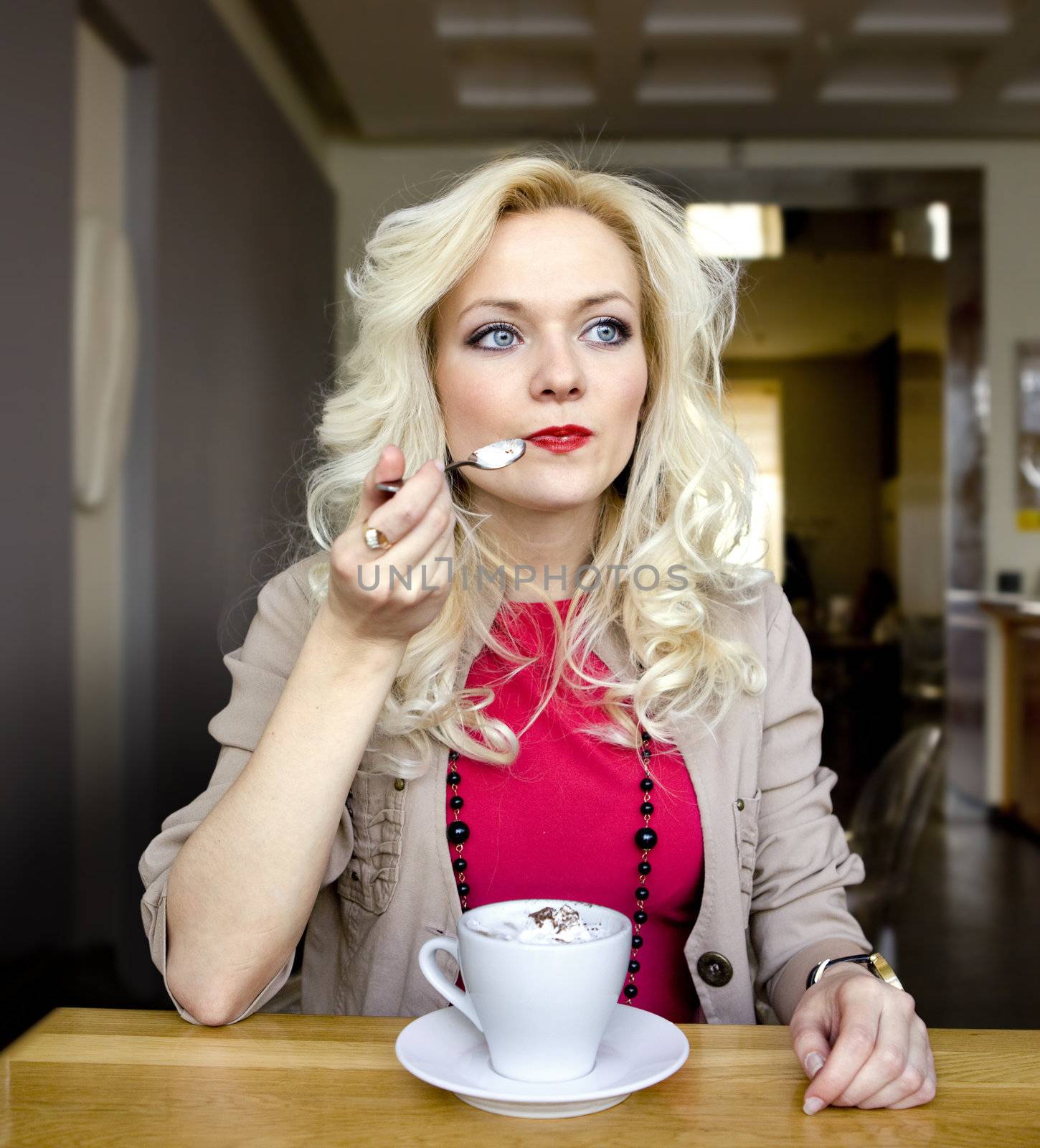 young blonde in cafe at little table with cup of coffee