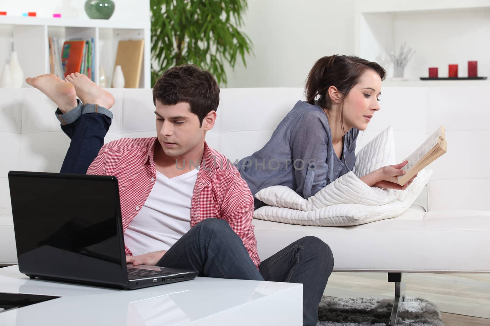 Couple reading a book and a laptop by phovoir