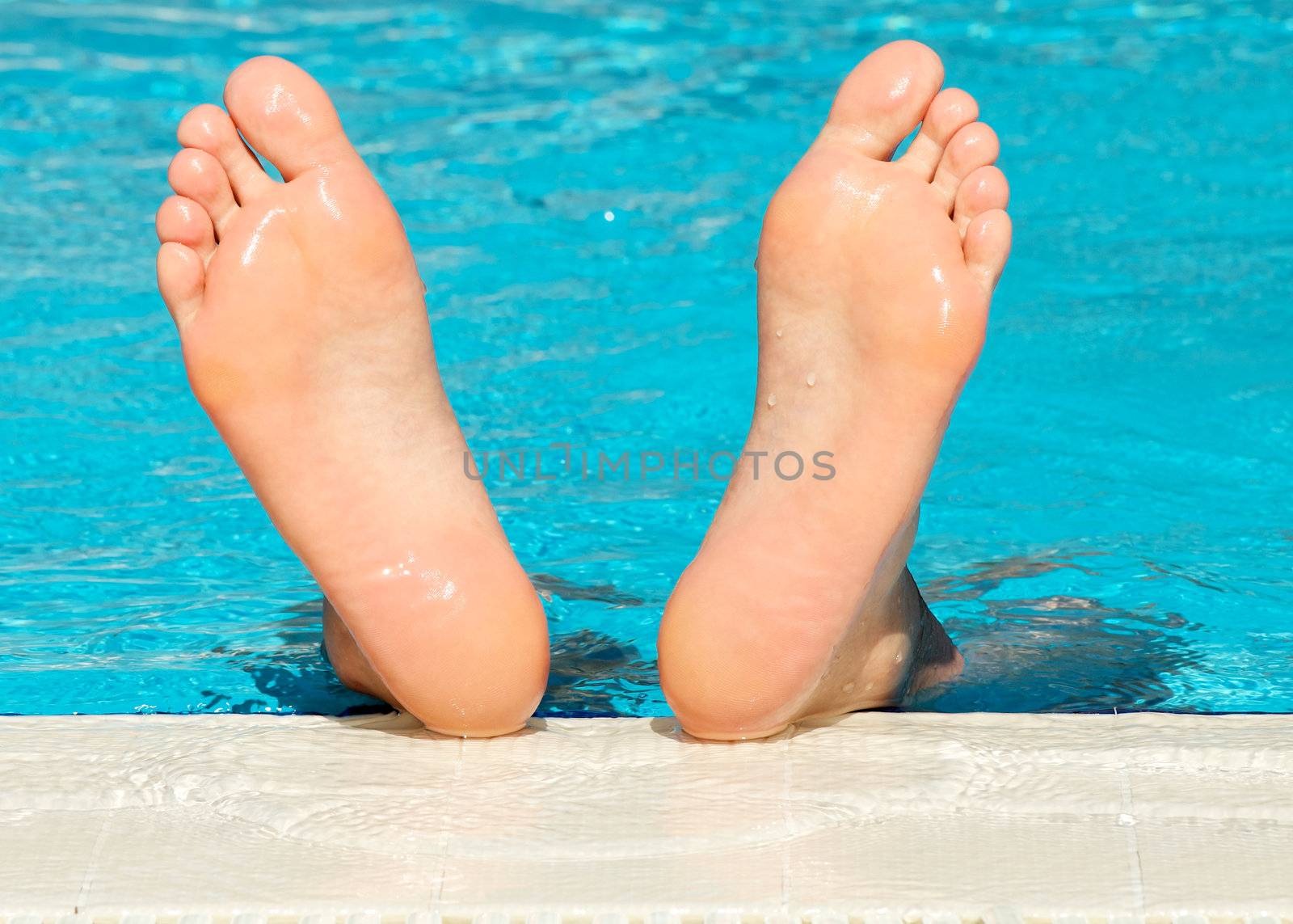 Man's feet with bright blue swimming pool background