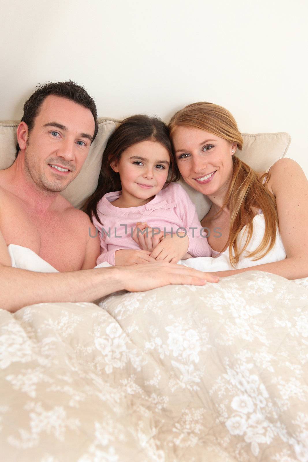 Couple in bed with their daughter by phovoir