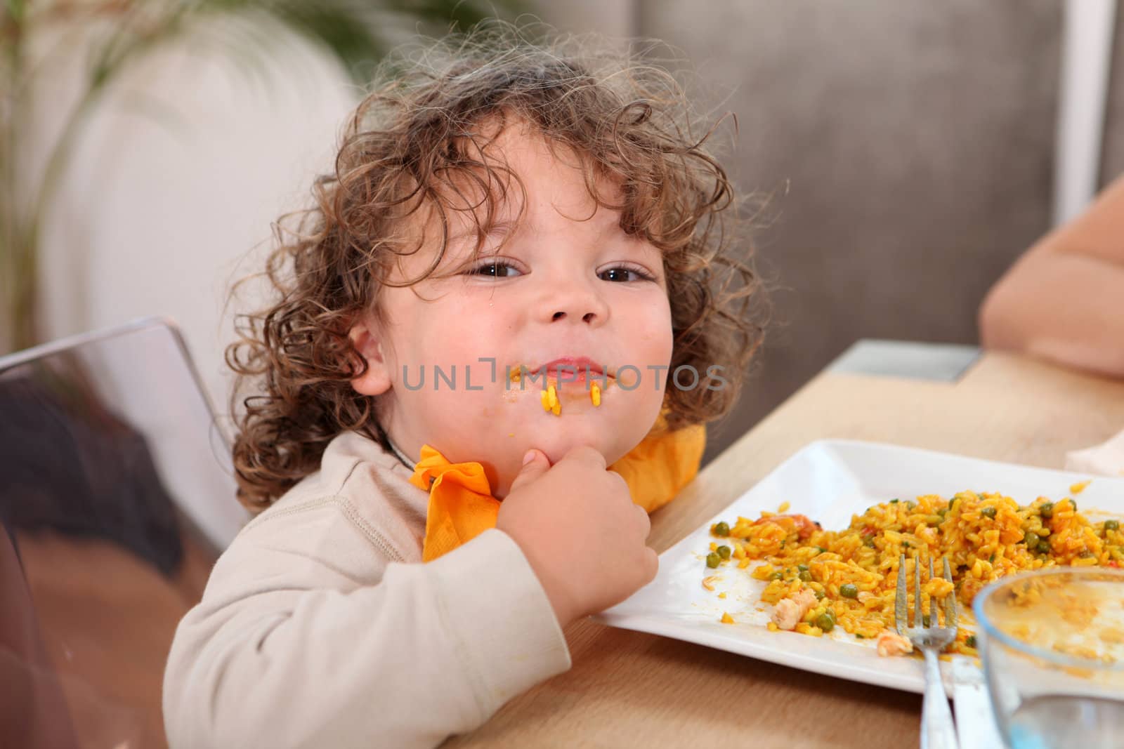 Little boy eating rice at kitchen table by phovoir
