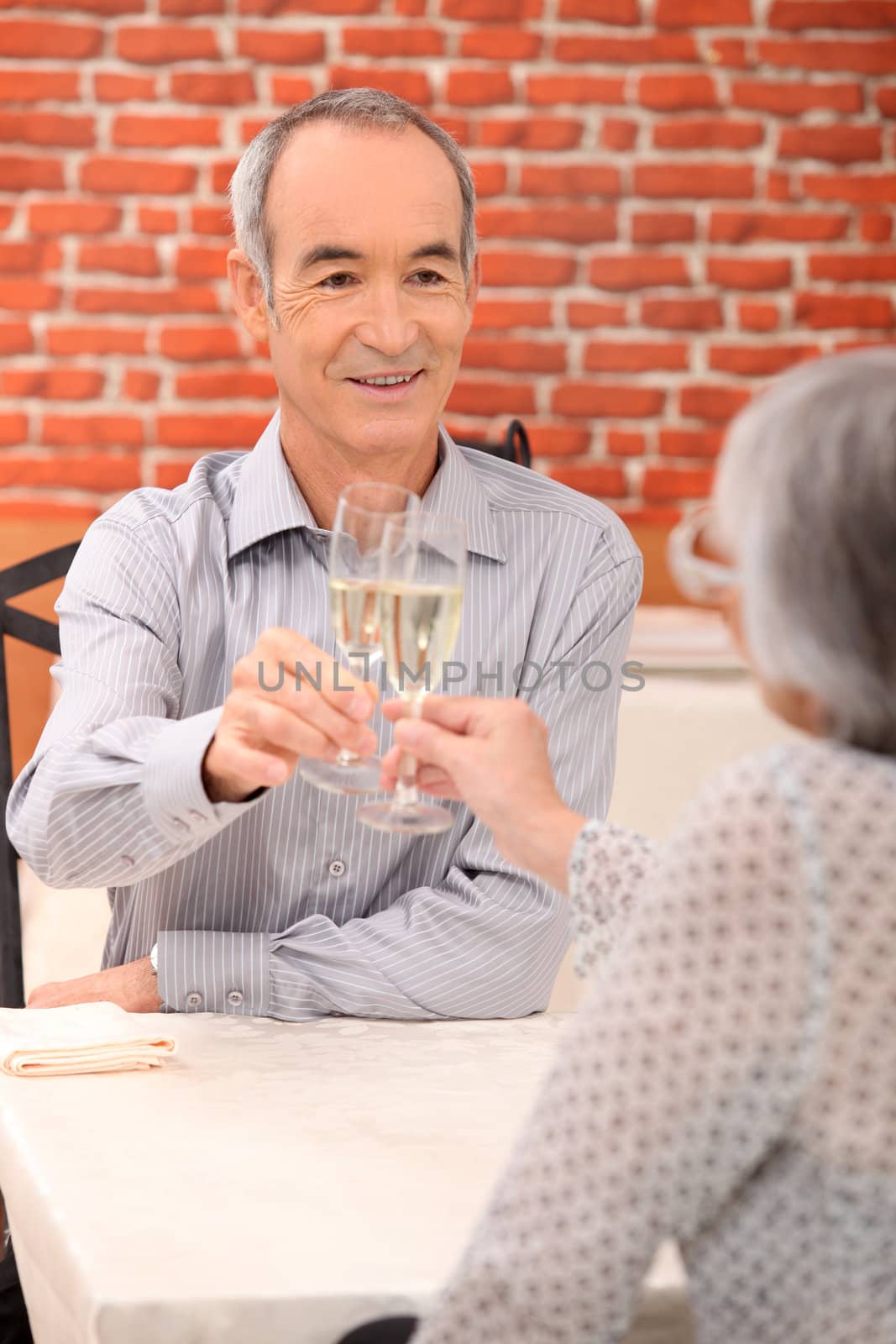 senior couple drinking champagne in a restaurant by phovoir