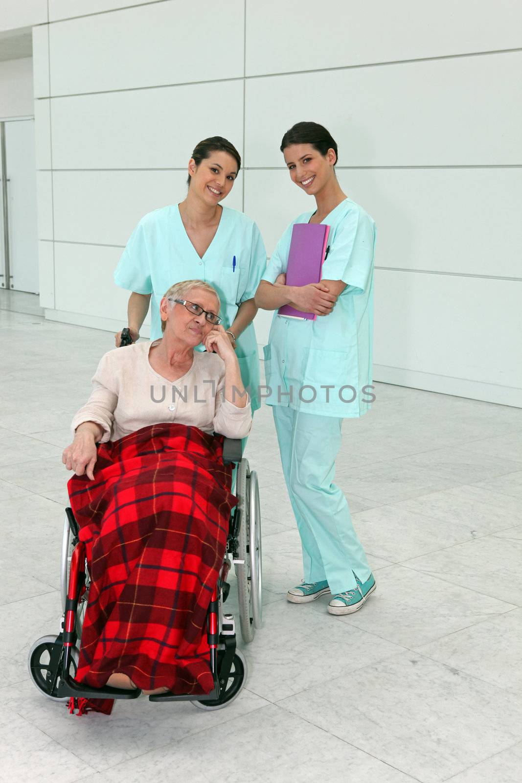 Cheerful nurses with senior woman in wheelchair