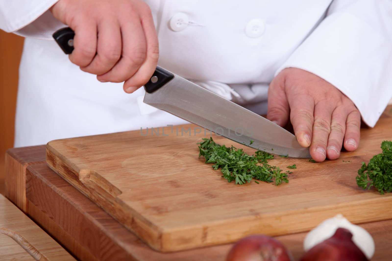 hands of cook cutting parsley by phovoir