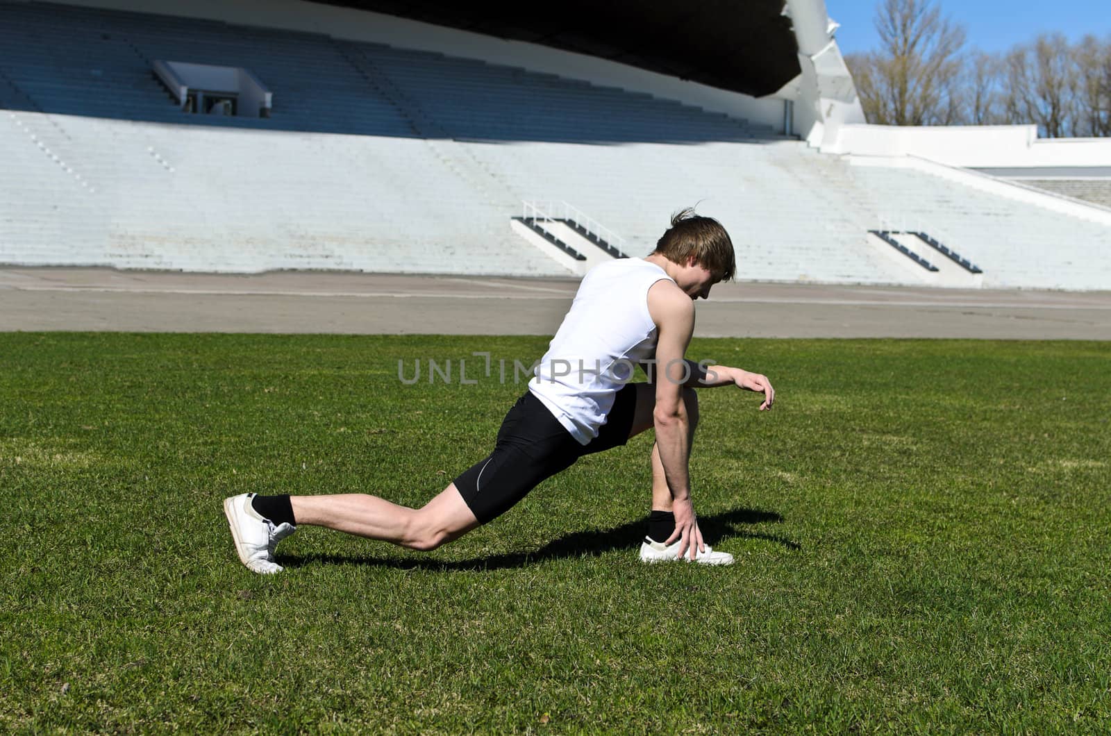 Runner at the city stadium warming and stretching